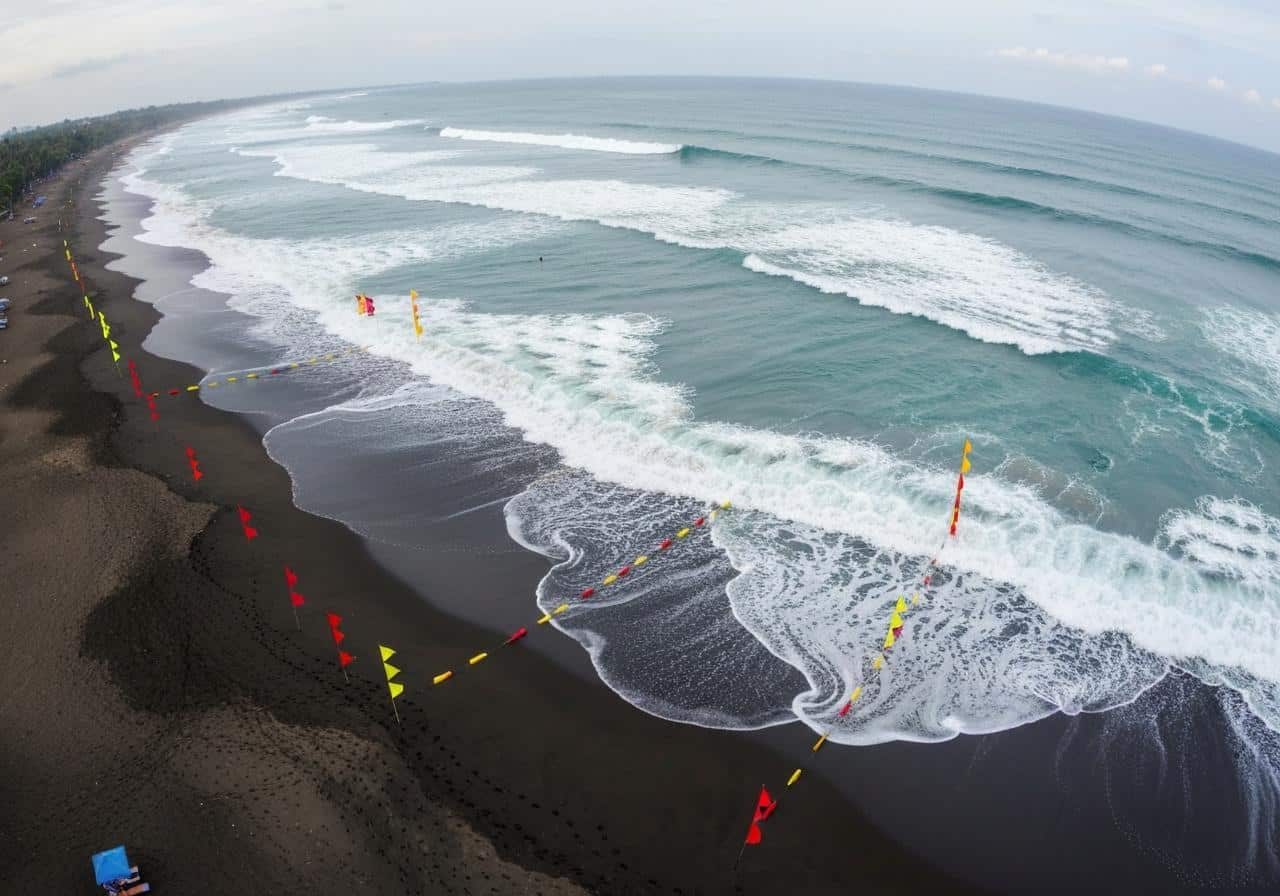 Plage de Kuta avec vagues et drapeaux de sécurité baignade